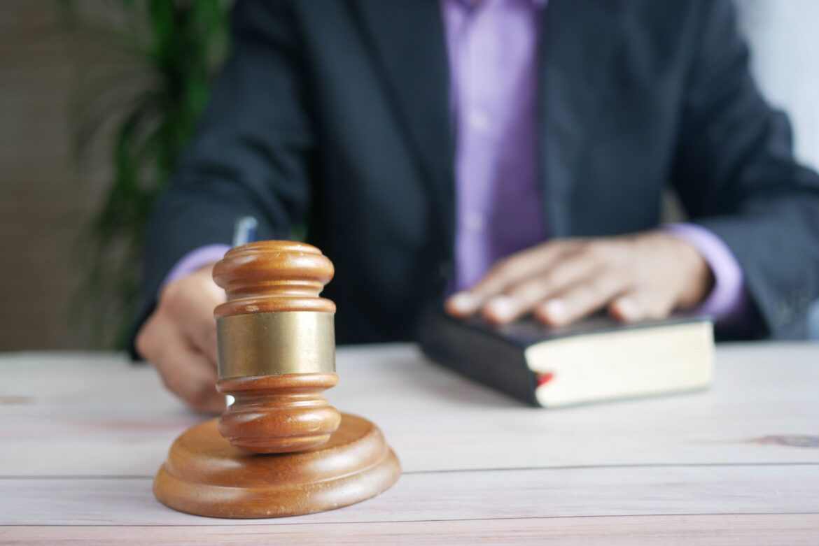 Un martello di legno e un libro legale rappresentano la giustizia in un contesto di tribunale, sottolineando l'ordine e l'autorità legale.